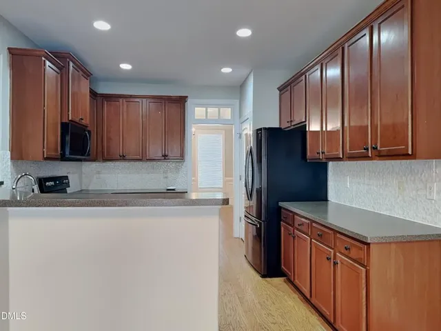 a kitchen with stainless steel appliances granite countertop a refrigerator a stove and a sink with wooden cabinets