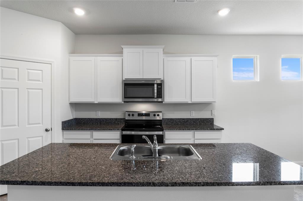 2025 Amazon Way Vero Beach, FL 32962 - Photo 8 of 33 a kitchen with granite countertop a stove a sink and a white cabinets