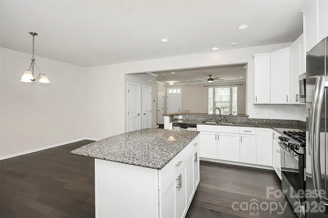 a kitchen with granite countertop kitchen island a sink appliances and cabinets
