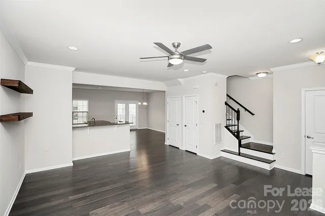 a view of an empty room with wooden floor and stairs