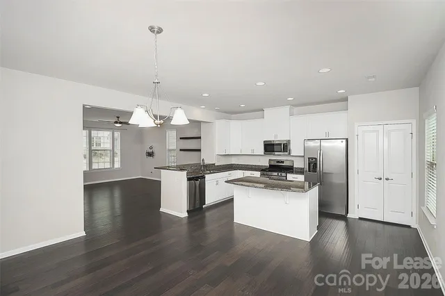 a kitchen with stainless steel appliances kitchen island granite countertop a refrigerator and a stove top oven