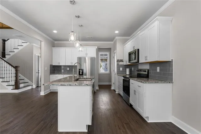 a kitchen with stainless steel appliances kitchen island granite countertop a stove a sink a refrigerator and cabinets