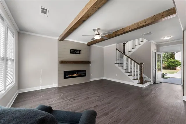 a view of an empty room with wooden floor a fireplace and a window