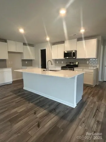 a large kitchen with stainless steel appliances a sink a stove a microwave a center island and cabinets