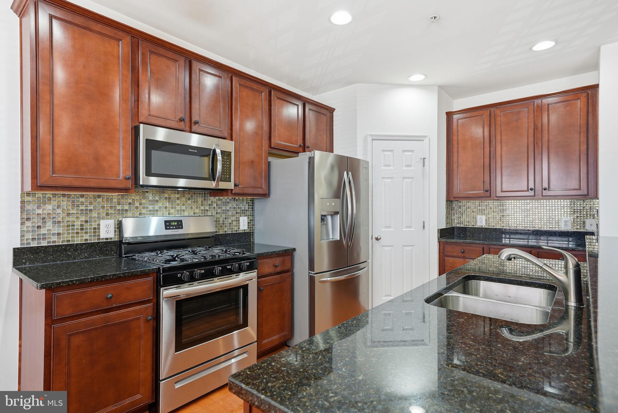 9539 Center Street Manassas, VA 20110 - Photo 18 of 41 a kitchen with granite countertop wooden cabinets stainless steel appliances and a window
