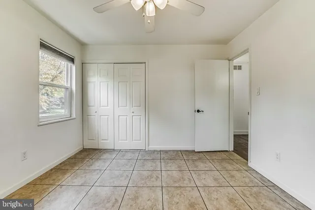 a view of an empty room with window and chandelier fan