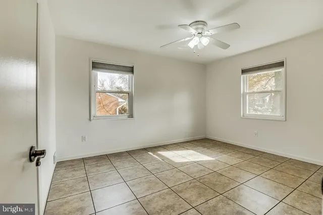 an empty room with windows and ceiling fan