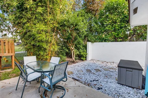 a patio with table and chairs and potted plants