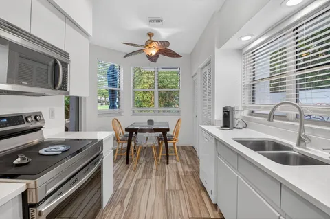 a kitchen with a stove a sink and wooden floor