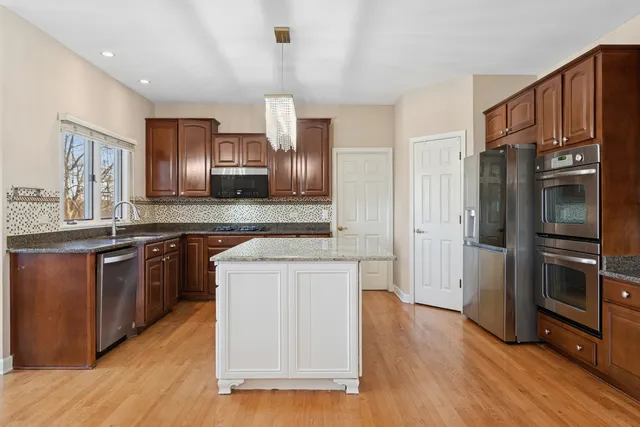 a kitchen with stainless steel appliances wooden cabinets and wooden floor