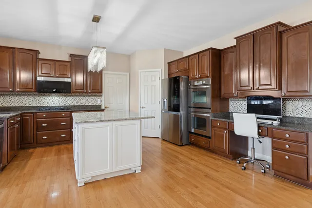 a kitchen with granite countertop wooden floors stainless steel appliances and cabinets