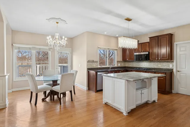 a kitchen with stainless steel appliances granite countertop a stove top oven a sink dishwasher a dining table and chairs with wooden floor