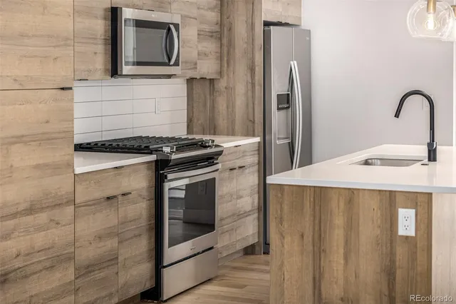 a kitchen with stainless steel appliances granite countertop a sink a stove and a wooden floors