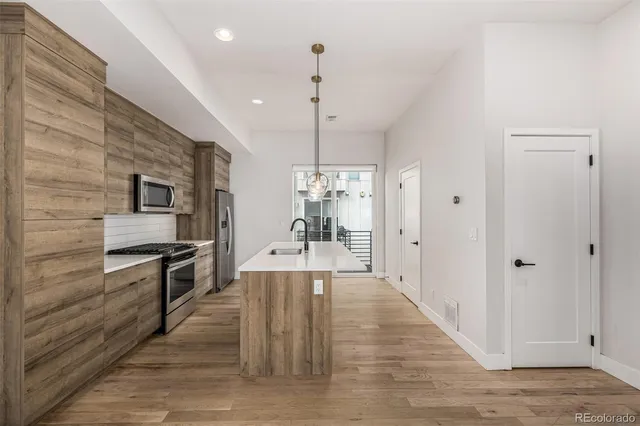 a kitchen with stainless steel appliances a kitchen island hardwood floor sink and stove