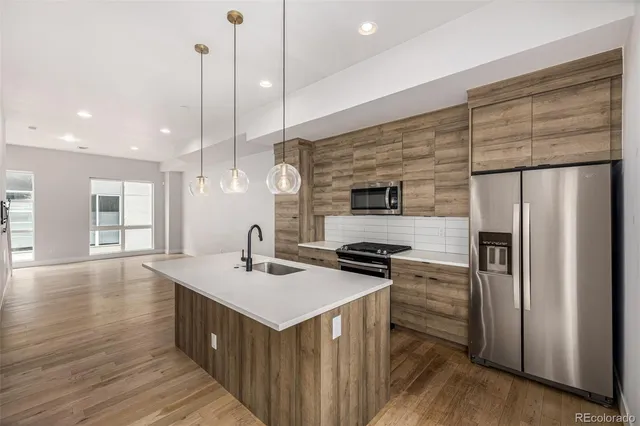 a kitchen with stainless steel appliances kitchen island granite countertop a stove a sink and a refrigerator