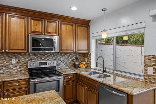 a kitchen with stainless steel appliances granite countertop a stove top oven a sink dishwasher a dining table and chairs with wooden floor