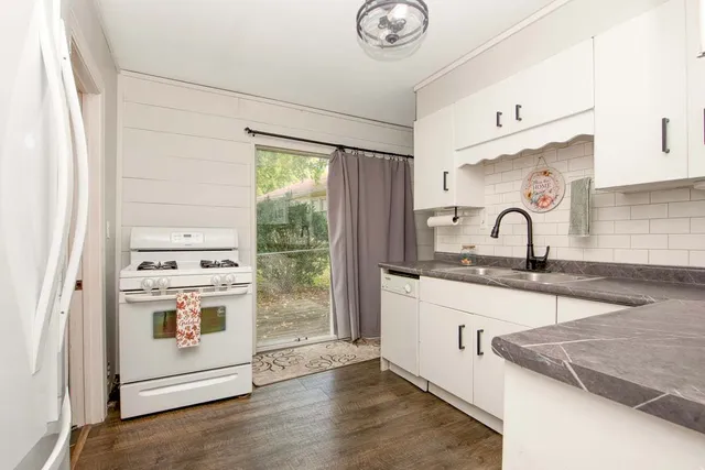 a kitchen with stainless steel appliances granite countertop a sink and a stove next to a window