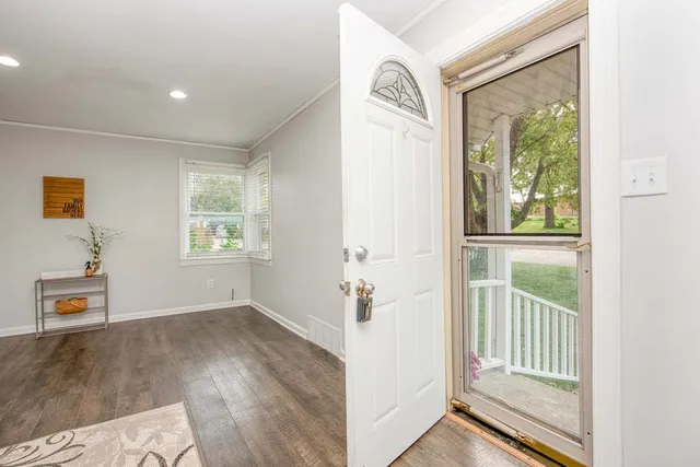 a view of a hallway to a bedroom with wooden floor and windows