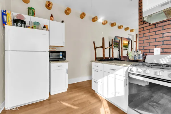 a kitchen with stainless steel appliances granite countertop a refrigerator a stove and a sink with wooden floor