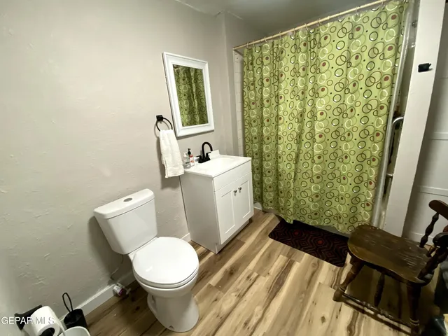 a white toilet sitting next to a bathroom sink and a wooden floor