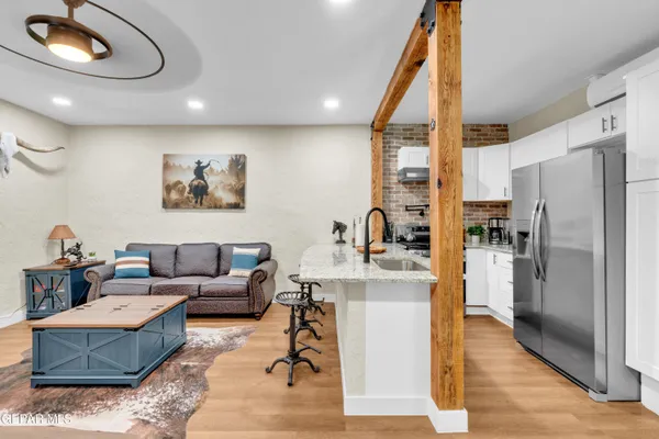 a living room with stainless steel appliances furniture and a kitchen view
