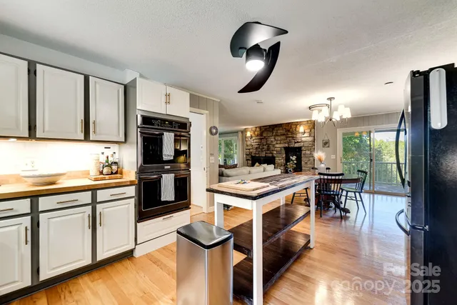 a kitchen with stainless steel appliances granite countertop a stove top oven a sink a dining table and chairs with wooden floor