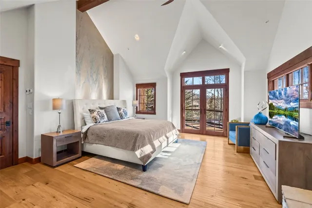 a spacious bedroom with a bed a dresser and a large window