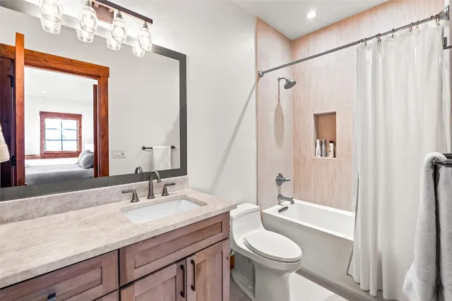 a bathroom with a granite countertop sink toilet a mirror and shower
