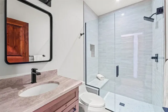 a bathroom with a granite countertop sink toilet a mirror and shower