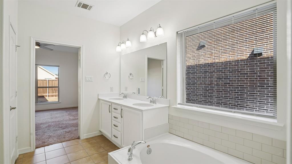 9904 Copperhead Lane McKinney, TX 75071 - Photo 23 of 40 Full bath featuring light tile patterned floors, a garden tub, double vanity, a ceiling fan, and light colored carpet