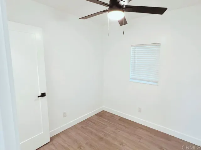 a view of a small space with wooden floor and a ceiling fan