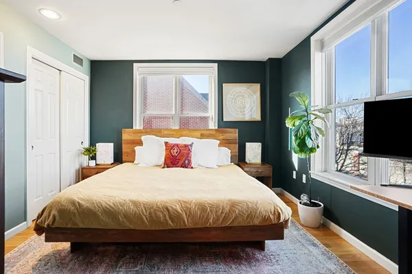 a bedroom with a bed table flat screen tv and a window