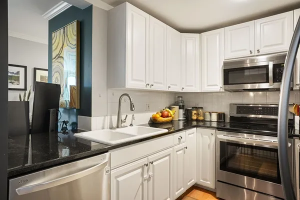a kitchen with granite countertop white cabinets stainless steel appliances and a sink
