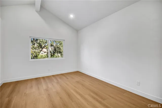 an empty room with wooden floor and window