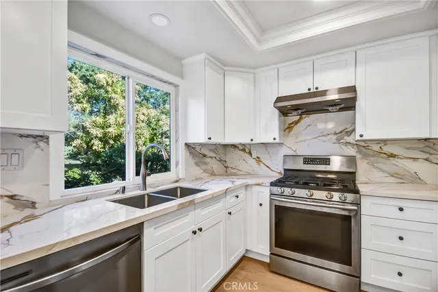 a kitchen with granite countertop a sink stainless steel appliances and cabinets