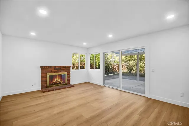 an empty room with wooden floor fireplace and windows