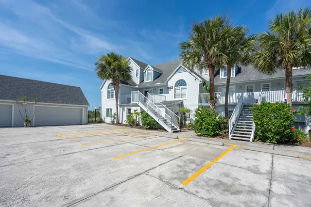 a front view of a house with a garden and palm trees