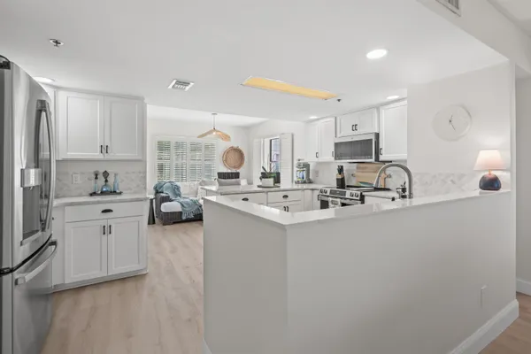 a kitchen with stainless steel appliances a sink a stove a refrigerator cabinets and a window