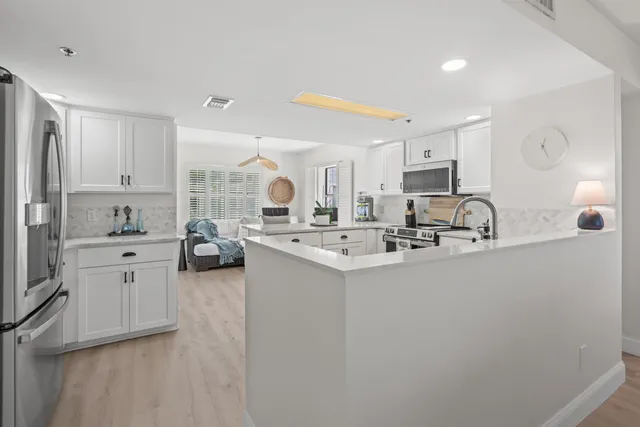 a kitchen with stainless steel appliances a sink a stove a refrigerator cabinets and a window