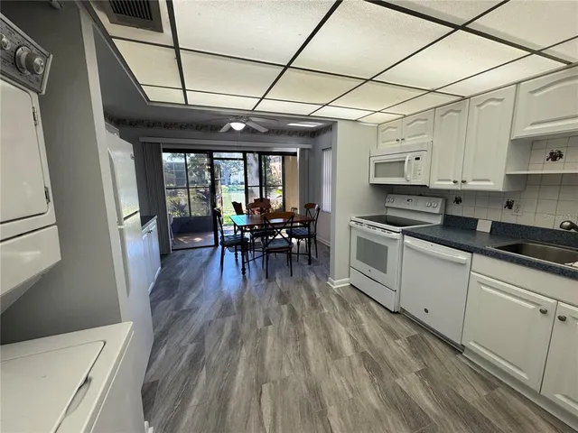 a kitchen with stainless steel appliances granite countertop a stove a refrigerator a sink a dining table and chairs with wooden floor