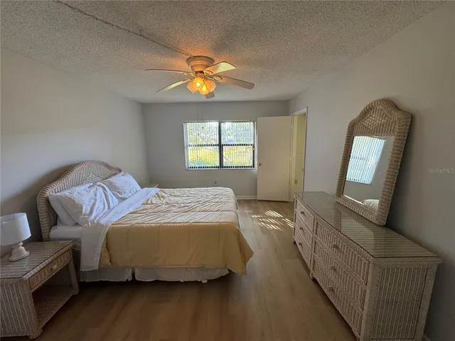 a bedroom with a bed a mirror on the dresser and a window