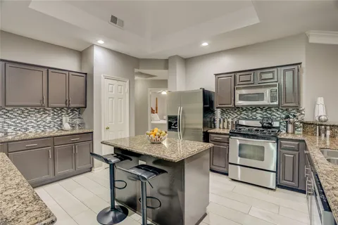 a kitchen with stainless steel appliances kitchen island granite countertop a stove refrigerator and cabinets