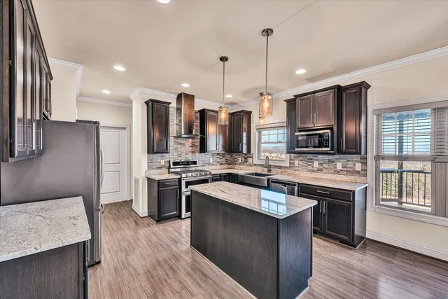 a kitchen with a stove a sink dishwasher a refrigerator and a oven with wooden floor