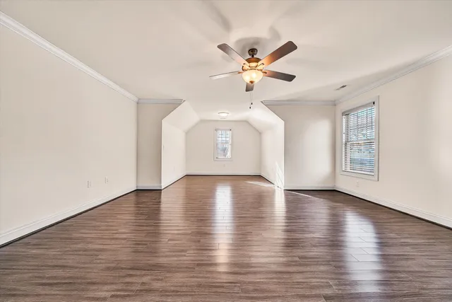 a view of an empty room with wooden floor and window
