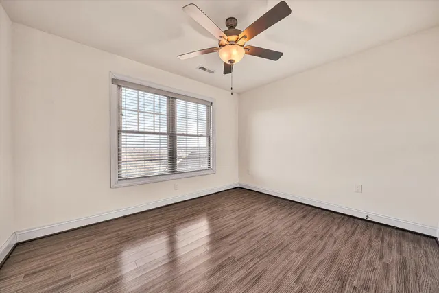 a view of empty room with wooden floor and fan