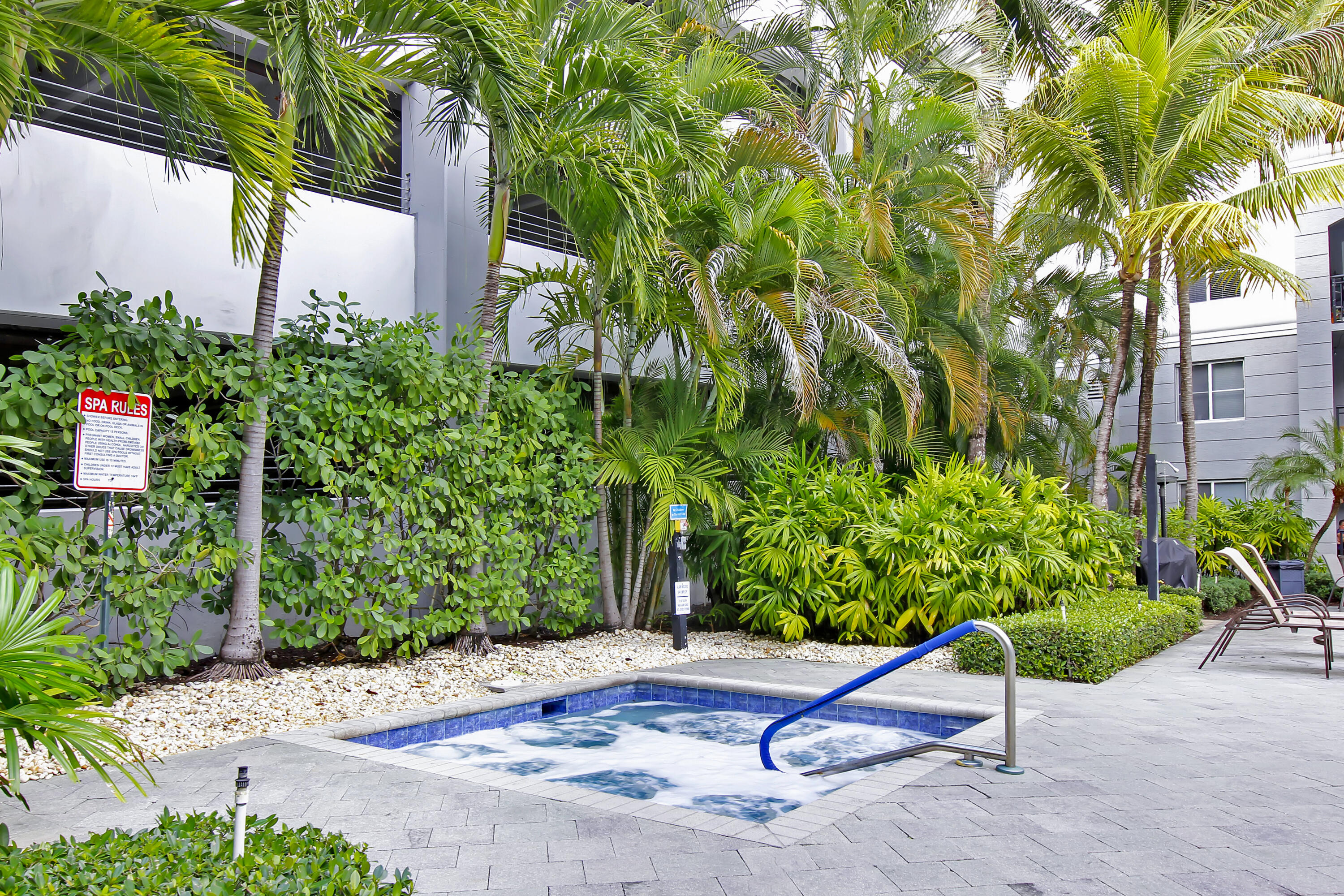 1660 Renaissance Commons Boulevard, Unit 2122 Boynton Beach, FL 33426 - Photo 19 of 38 a wooden bench sitting in a yard with potted plants