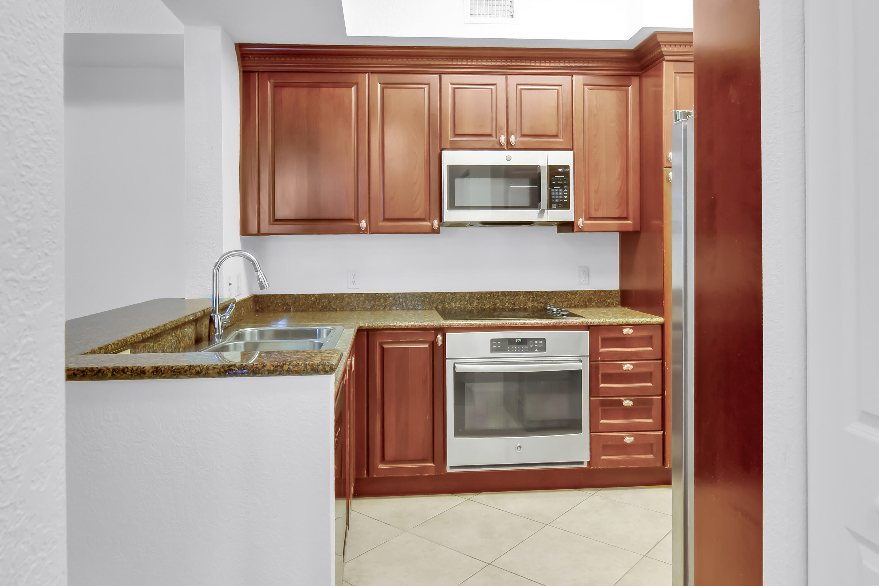 1660 Renaissance Commons Boulevard, Unit 2122 Boynton Beach, FL 33426 - Photo 31 of 38 a kitchen with granite countertop a sink and a stove top oven