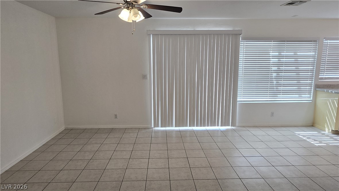 3849 Reflection Way Las Vegas, NV 89147 - Photo 6 of 25 This living area features a clean tile floor, a ceiling fan, and ample natural light from the large windows and sliding glass door.