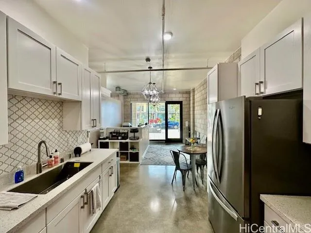 a kitchen with granite countertop a refrigerator a sink a stove and cabinets