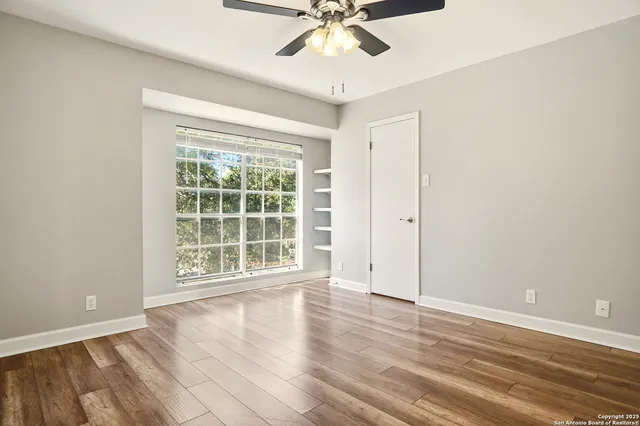 an empty room with wooden floor and ceiling fan